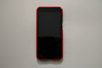 Black smartphone with red case on a light gray background