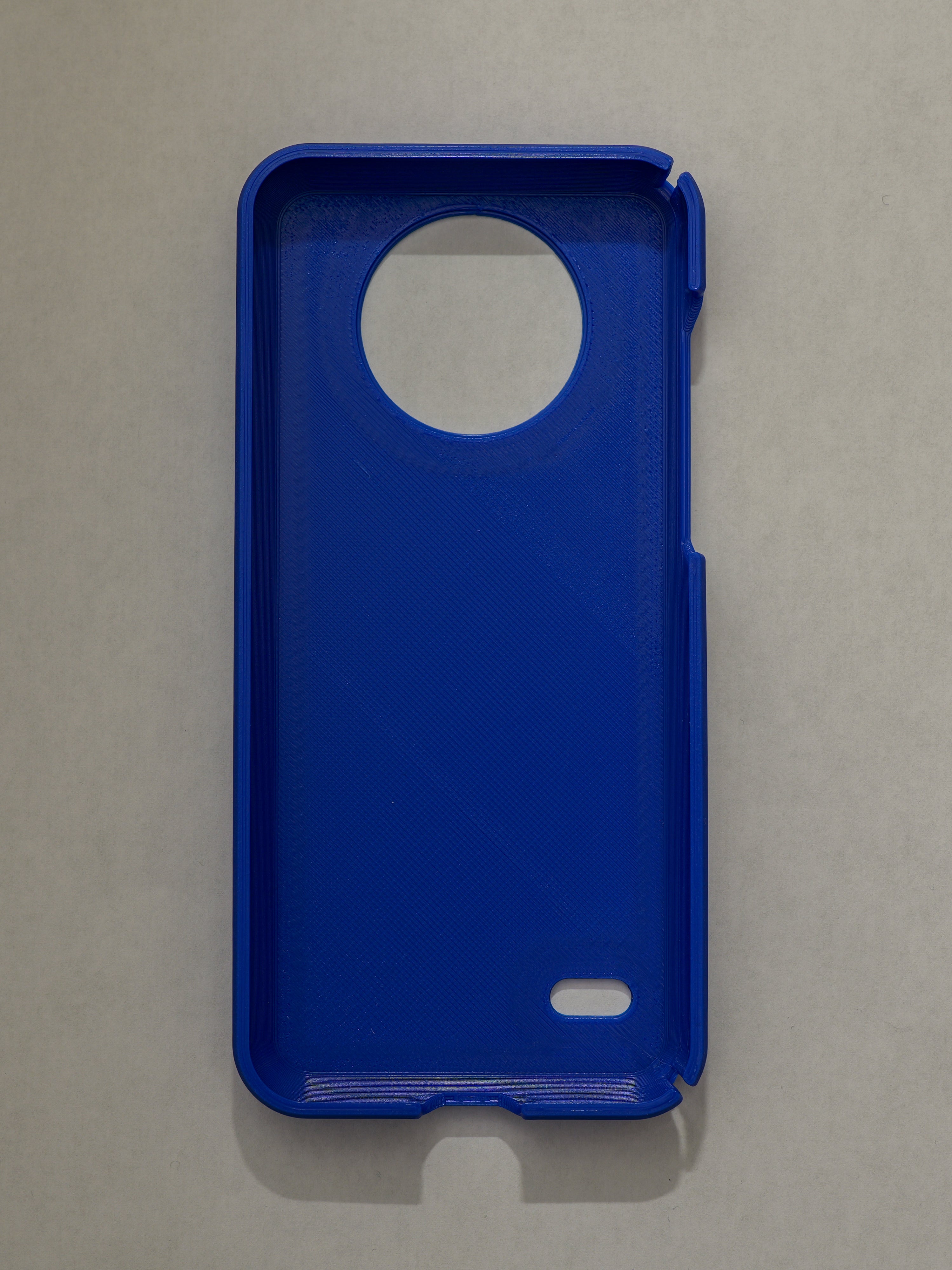 Blue phone case with a circular cutout on a gray background