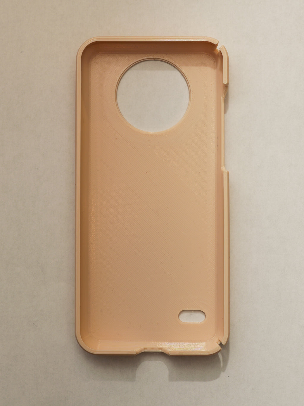Beige phone case with a circular cutout on a beige background