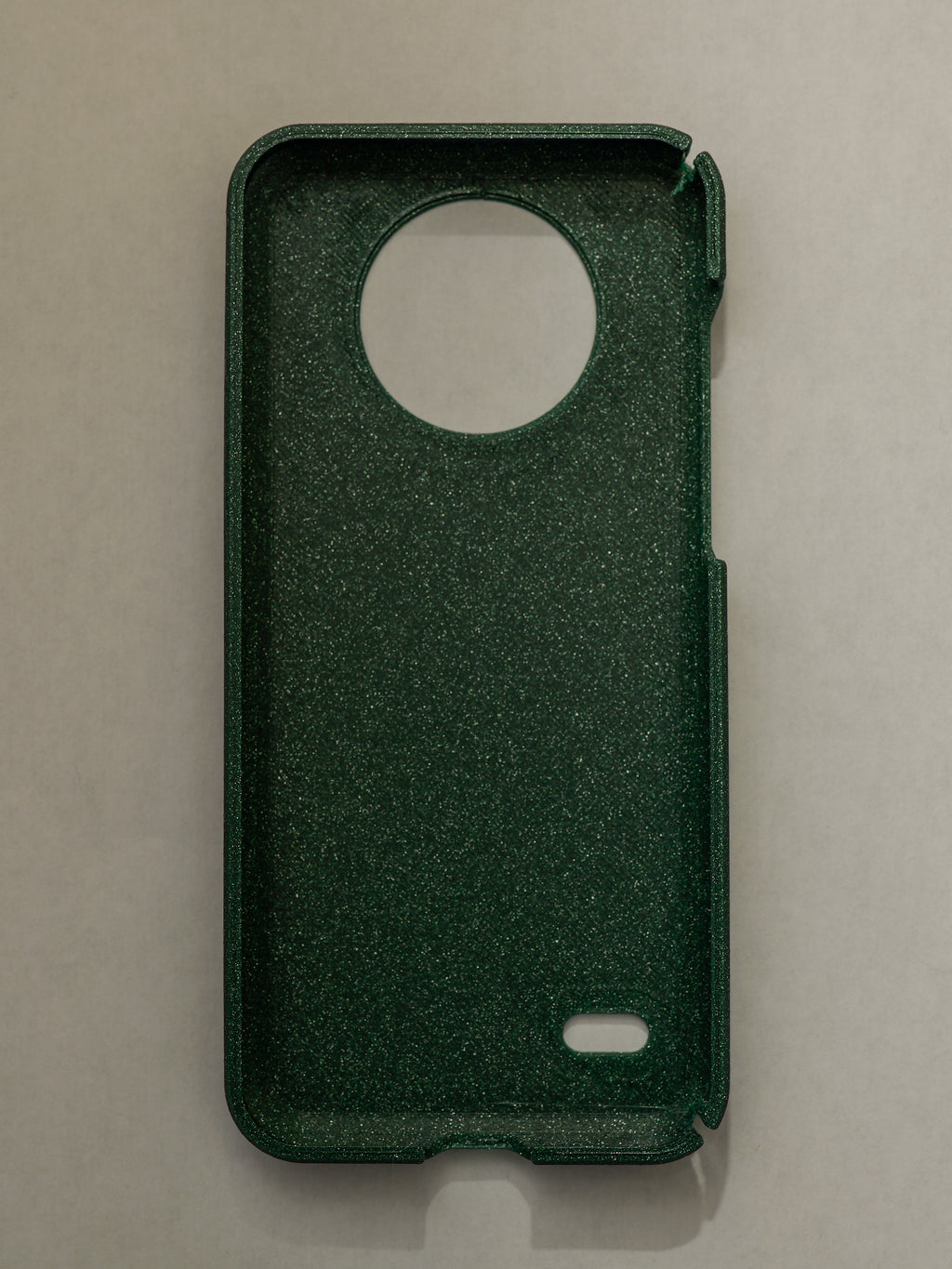 Green phone case with a circular cutout on a beige background