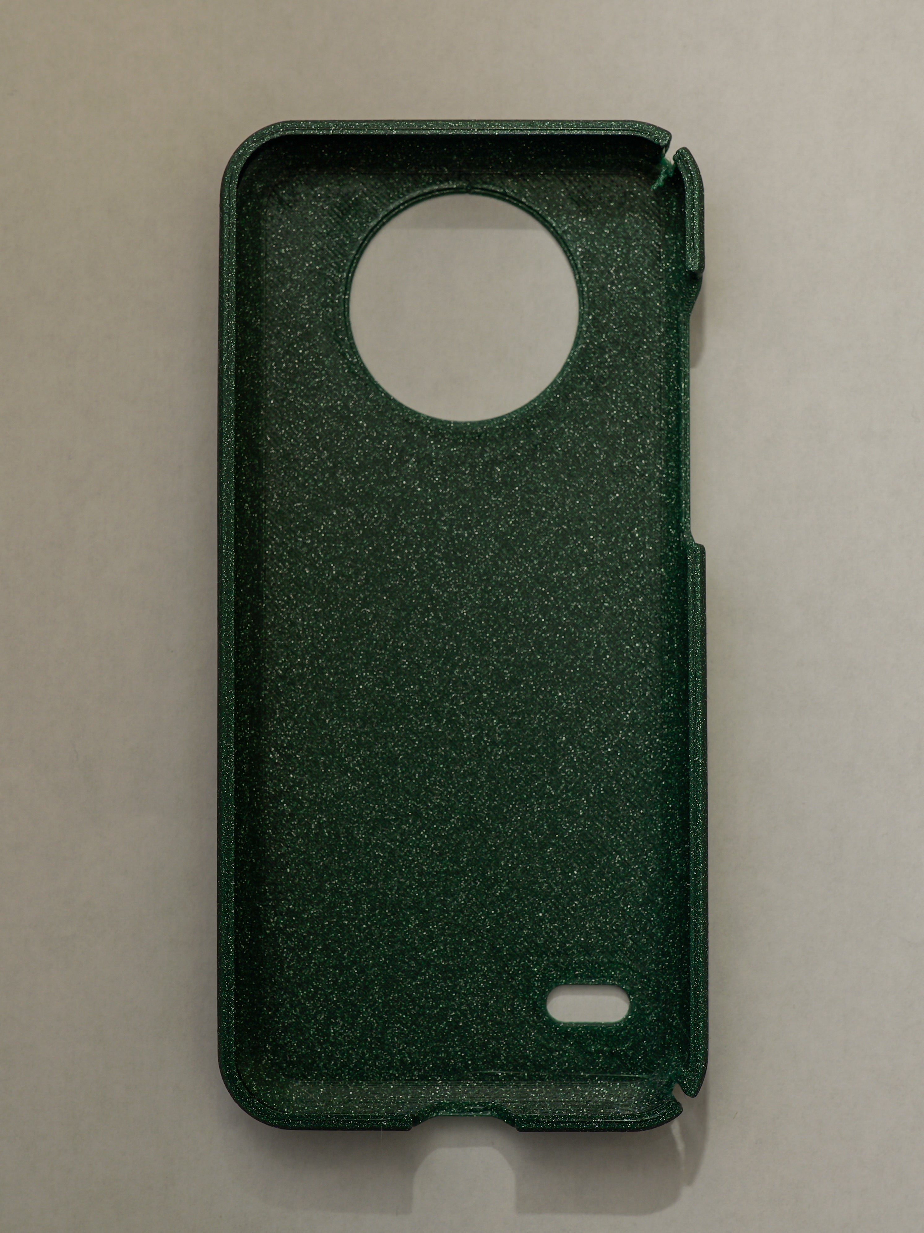 Green phone case with a circular cutout on a beige background